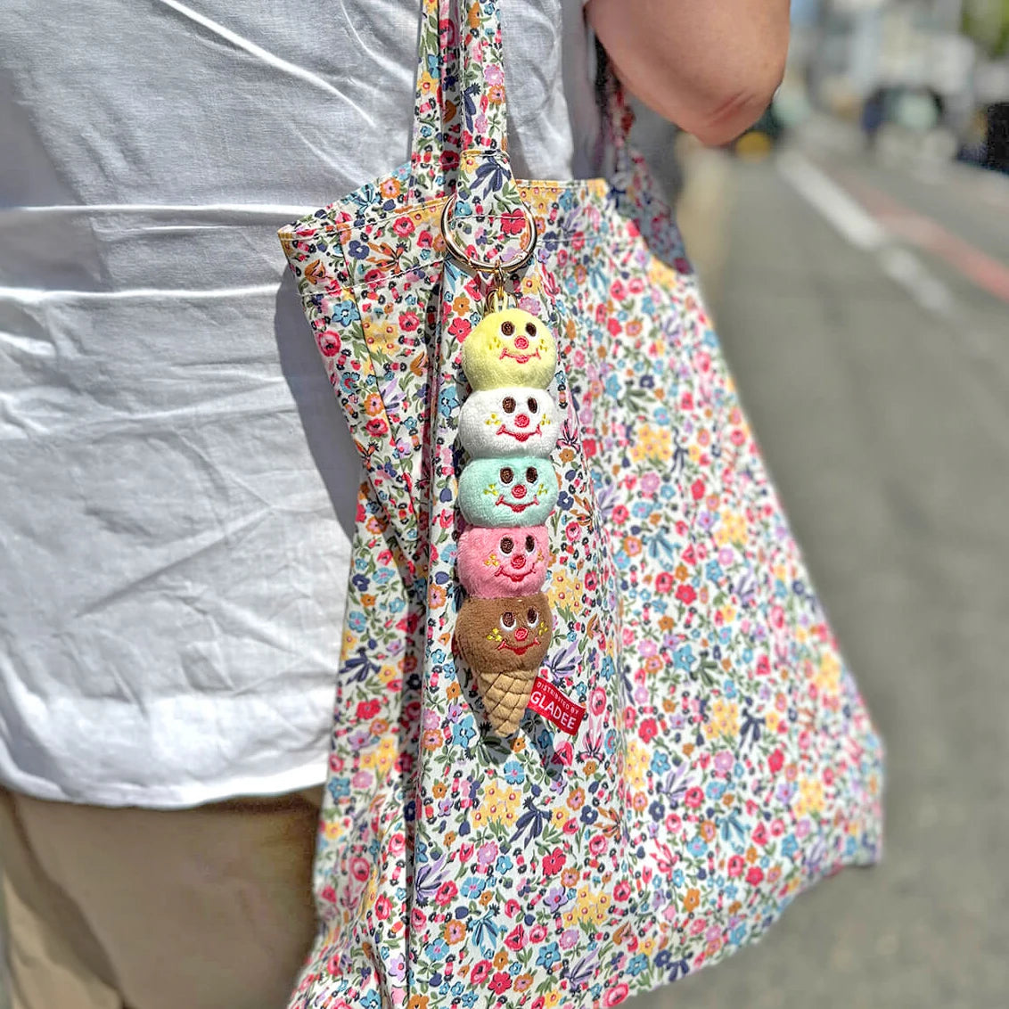 Five-scoop plush ice cream keychain hanging from a floral tote bag, gold ring at top
