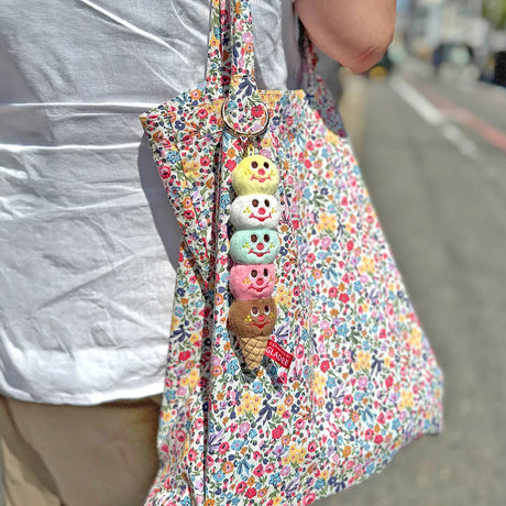 Five-scoop plush ice cream keychain hanging from a floral tote bag, gold ring at top
