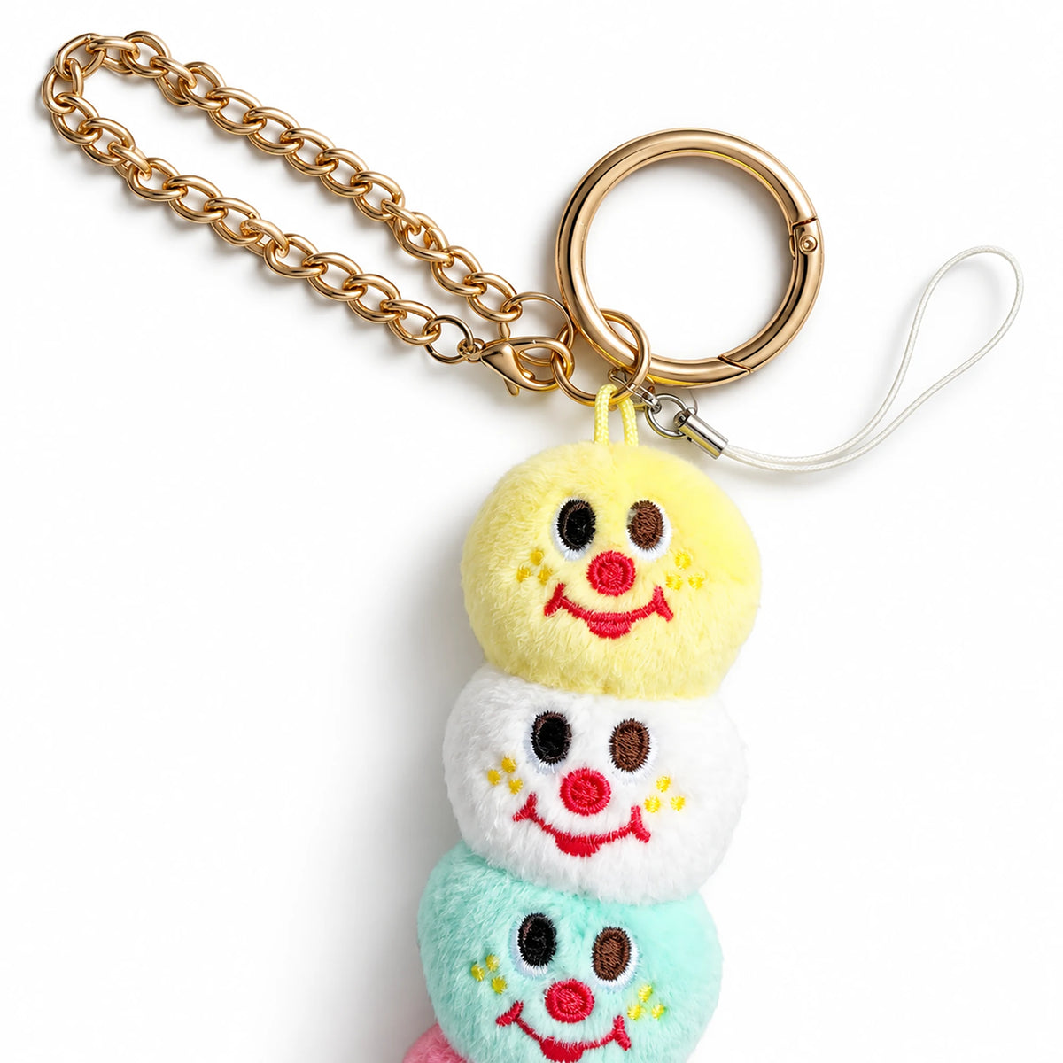 Five-scoop plush ice cream keychain close-up with smiling scoops and braided gold chain
