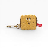 Plush cookie-shaped AirPods case with cookie face, zipper, and metal carabiner clip