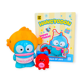 Blue character figurine with an orange fish hat holding a welcome sign, red octopus toy, and colorful Happy Birthday box