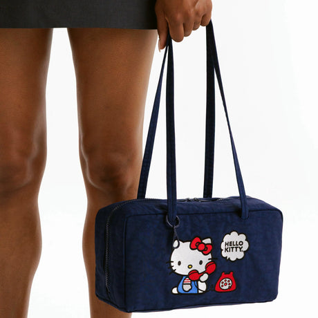 Close-up of model holding navy Hello Kitty x Baggu Nylon Bowler Bag with red phone graphic and long shoulder straps, promo image 2