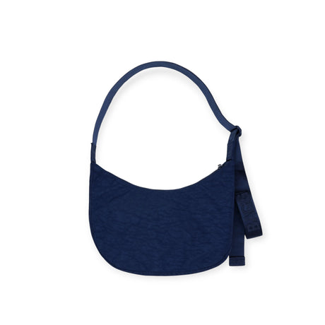 The Hello Kitty x Baggu Medium Nylon Crescent - Teddy is a limited edition navy shoulder bag with a curved shape, single strap, and side tag detail by Baggu, shown against a white background.
