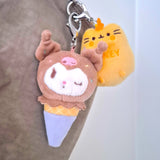 Two adorable plush keychain toys: one depicting a bear atop an ice cream cone and the other featuring a yellow cat labeled "Honey." Add an element of surprise with our Hello Kitty & Friends Keychain from the Ice Cream Blind Box, inspired by the whimsical world of Sanrio. Perfect for collectors and fans alike!