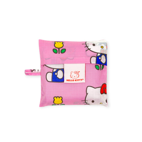 The Standard Baggu - Hello Kitty - Pink by Baggu is a limited edition pink pouch with yellow flower designs and a white Hello Kitty logo tag—ideal as a reusable bag for carrying daily essentials.