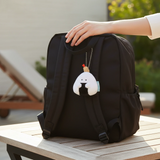 Plush rice ball keychain hanging from backpack, white with black center and bead chain
