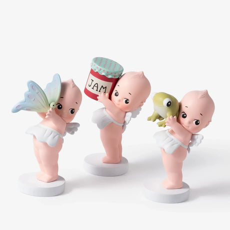 Smoko’s Kewpie Holding Things Blind Box features adorable vinyl figurines—each with white wings, standing on round bases, holding items like a butterfly, a "JAM" jar, or a green frog—perfect for any Kewpie collection.