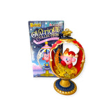 A pink figurine with a crown sits inside a decorative egg-shaped display from Re-Ment's Kirby Ovaltique Globe Blind Box. The ornate design includes a pedestal base, and the matching box in the background evokes Antique-Inspired Globes.