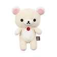The Korilakkuma Small Plush - 20cm by Rilakkuma is a beige bear with pink ears, black eyes, a red chest button, and a “Rilakkuma” side tag, standing upright against a white background.