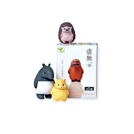 Three adorable Kyomu Animals figurines, featuring a hedgehog and a bear, adorn and stand in front of a white Blind Box with Japanese text. These Yell brand figures add charm to any setting.