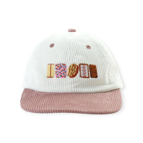 White ribbed knit baseball cap with mauve brim and embroidered colorful lettering