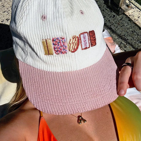 Cream and dusty pink corduroy hat embroidered with colorful classic Australian biscuit designs on front panel