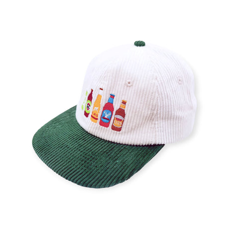 The Lies Collective Hat - Great Aussie Beer Lid by Lies Collective is a white corduroy baseball cap with a green brim, featuring five colorful embroidered bottles on the front.