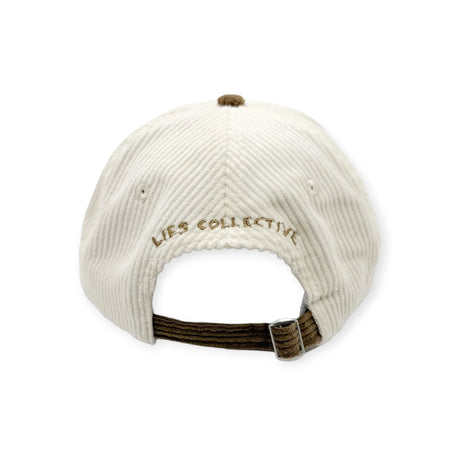 Rear view of white corduroy cap with brown adjustable strap and embroidered Lies Collective logo above opening