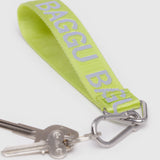 The Baggu Logo Keychain in Citron is a vibrant lime green keychain made from recycled nylon, featuring "BAGGU" in white letters. It securely attaches to two keys with a metal clip.