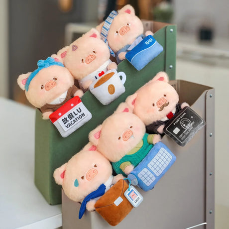 Assorted office plush piggy keychain blind box figures in a green container.