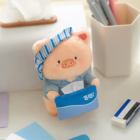 Plush piggy keychain in blue shirt and striped cap, sitting holding a blue notebook.
