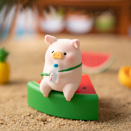 LuLu the Piggy figurine sitting on a watermelon slice holding a small bottled drink on sandy beach surface