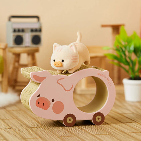 LuLu the Piggy figurine dressed as a cat on a pig-shaped pink scratcher with wooden floor background