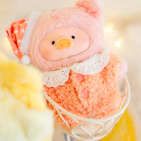 Soft LuLu Piggy plush keychain in coral fuzzy pajamas with lace collar and star-patterned sleep cap on cozy chair