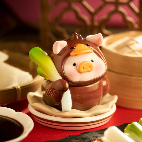 Cute pig figurine dressed in brown outfit with duck bill hood holding green vegetable on a white dish