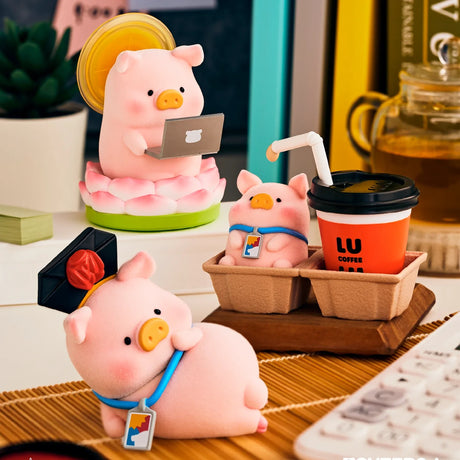 Piggy blind box figure sitting by a phone and a LU coffee cup on a desk