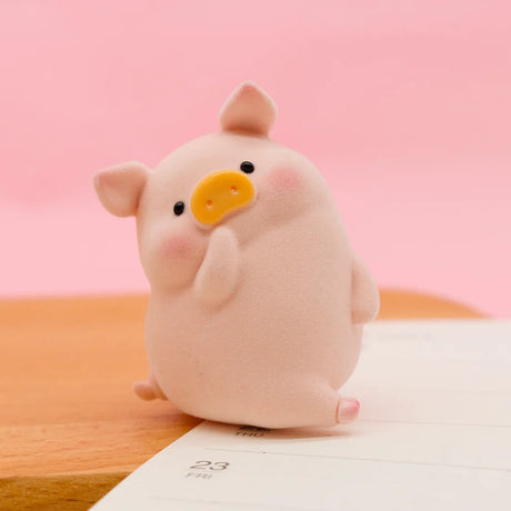 Close-up of LuLu the Piggy Original Series 2 figure 3 with soft texture and pink blush sitting on calendar page