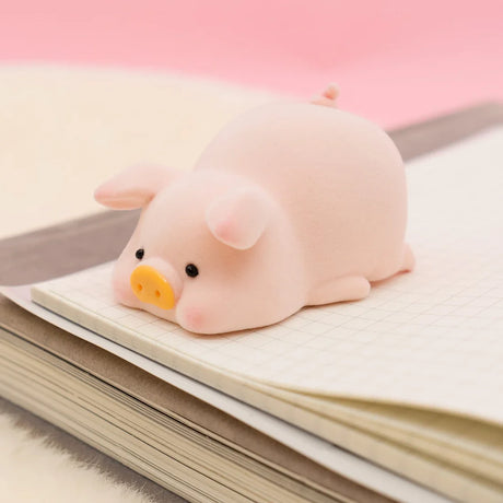 LuLu the Piggy Original Series 2 figure 4 with soft texture and yellow snout lying on open notebook with grid paper