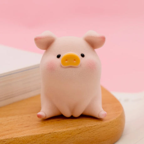 LuLu the Piggy Original Series 2 figure 7 with soft texture and yellow snout sitting on wooden surface against pink background