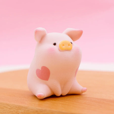 LuLu the Piggy Original Series 2 figure 7 with soft texture and red heart markings sitting on wooden surface with pink background