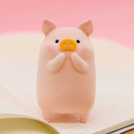 LuLu the Piggy Original Series 2 figure 9 with soft texture and shy pose on open notebook against pink background
