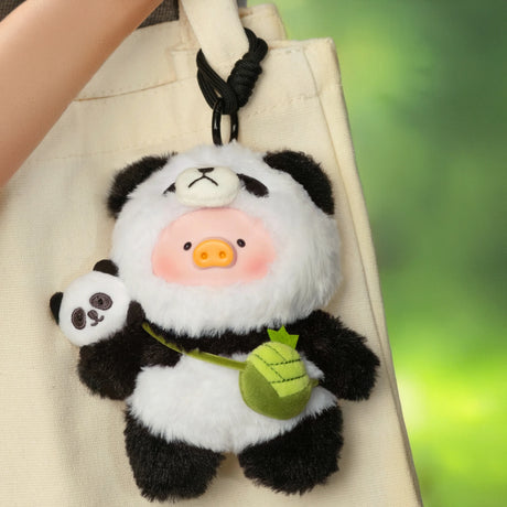 Close-up of LuLu the Piggy plush keychain in panda costume holding small panda plush and green leaf bag, hanging on tote bag