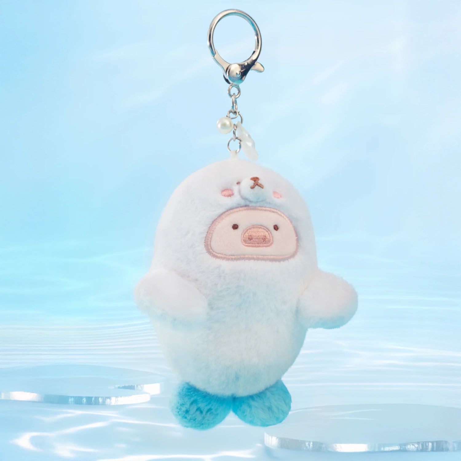 The LuLu the Piggy - Baby Seal LuLu Plush Keychain by LuLu The Piggy features a cute white and blue seal with a bear face—an adorable accessory for your next ocean adventure.