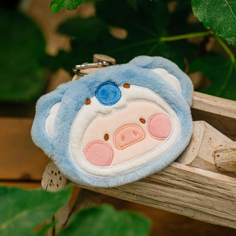 LuLu The Piggy Animal Party Pouch in koala design with keychain resting on wooden surface surrounded by green leaves