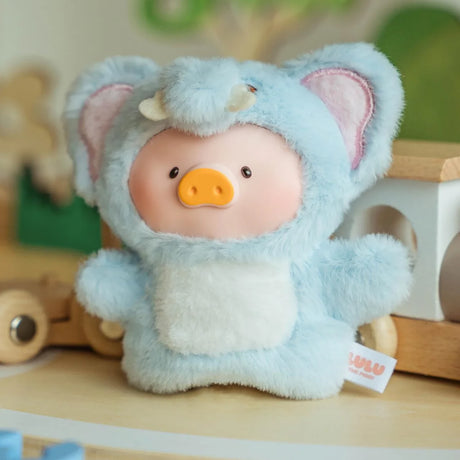 The LuLu The Piggy - Animal Party Puppet Keychain Blind Box by LuLu The Piggy features a plush toy in a blue elephant costume, shown on a wooden surface with toy blocks—an adorable collectible for any animal party fan.