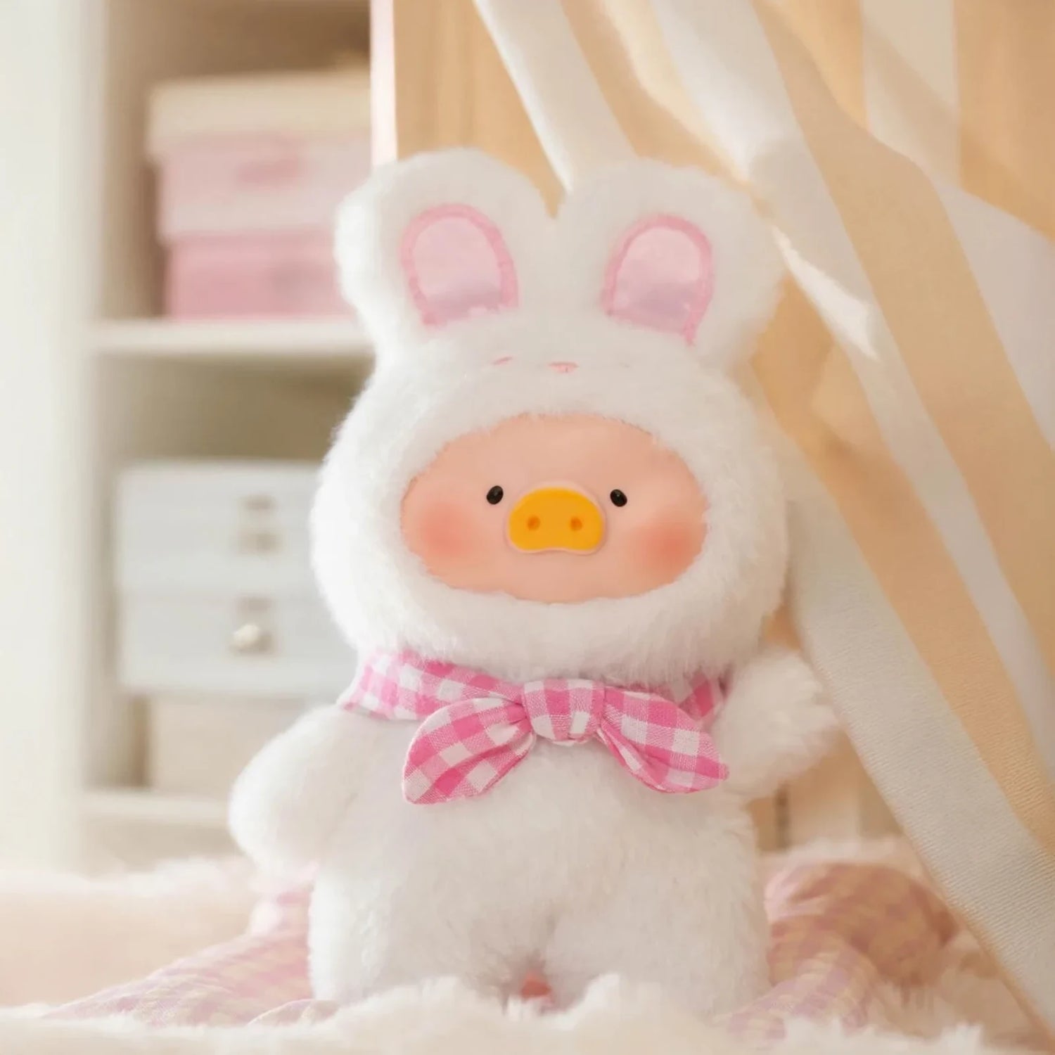 The Joyful Time LuLu The Piggy Plush Pal - Blind Box by LuLu The Piggy features a surprise keychain plush of Lulu dressed in a fluffy white bunny suit with a pink checkered bow, perfect for display or carrying anywhere.