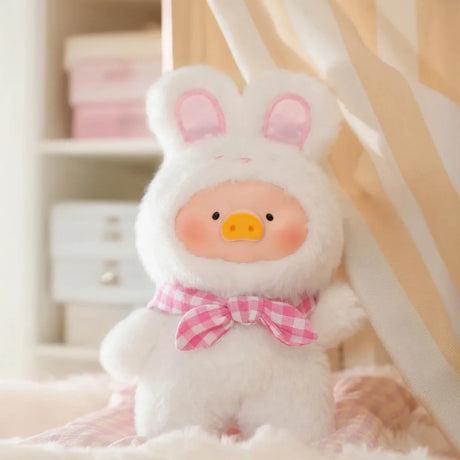 The Joyful Time LuLu The Piggy Plush Pal - Blind Box by LuLu The Piggy features a surprise keychain plush of Lulu dressed in a fluffy white bunny suit with a pink checkered bow, perfect for display or carrying anywhere.