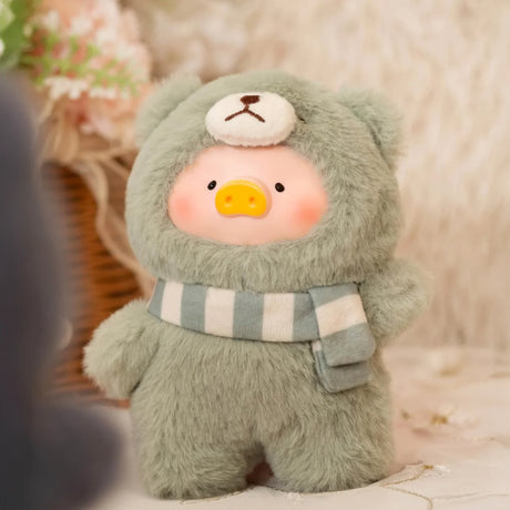 The Joyful Time Lulu The Piggy Plush Pal - Blind Box by LuLu The Piggy features LuLu in a fuzzy light green bear costume with a striped scarf, displayed indoors against a soft background.