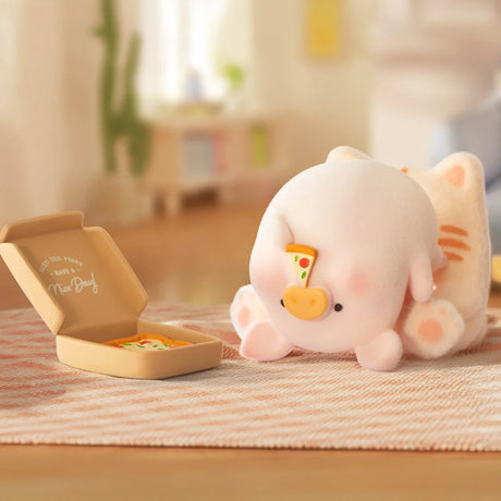 A plush cat toy with a pizza slice on its nose sits by an open pizza box—evoking the LuLu The Piggy - Stay With You Blind Box collectible from LuLu The Piggy—in a softly lit room.