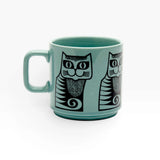 Teal ceramic mug with black cat face print and geometric accents