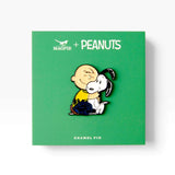 Enamel pin on green PEANUTS card with cartoon dog hugging a white puppy