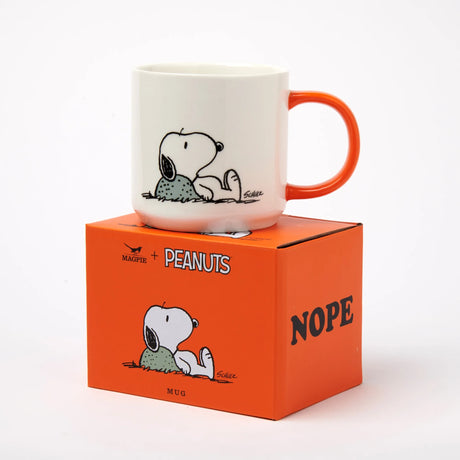 White ceramic mug with orange handle and Snoopy holding a bird graphic.