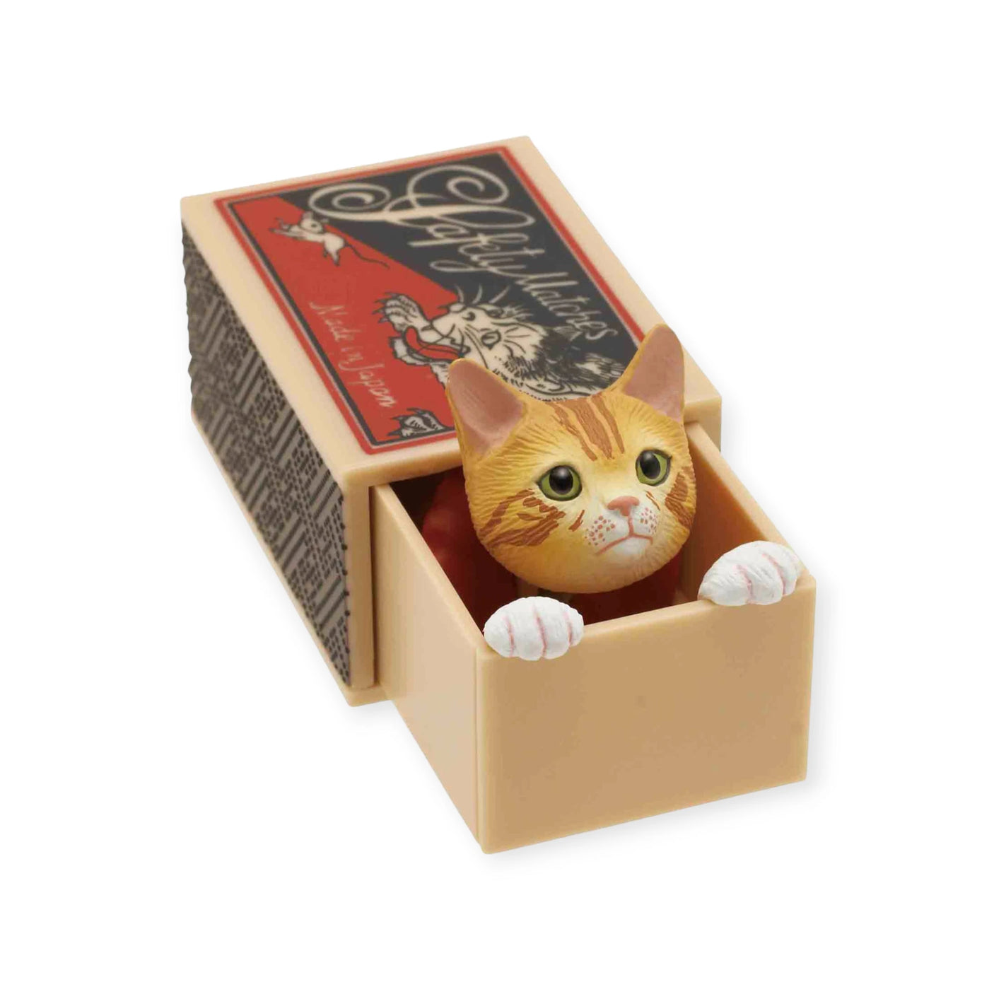 Toy of a ginger kitty peeking out of a beige blind box featuring vintage-style graphics on the lid, named the Cat in a Matchbox Blind Box by Kitan Club.