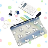 A transparent 19cm Miffy Bunny Print Case - Black from Miffy, made of soft silicone, holds pens and scissors. Nearby are a calculator, binder clips, and ruler on a polka dot background.