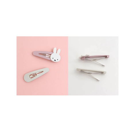 Two hair clips on a split background: a Miffy snap clip with a bunny shape on ivory, and another with a minimalist design on purple, both from the Miffy Snap Hair Clips - Ivory & Purple set. The reverse shows the opened metal fastenings.