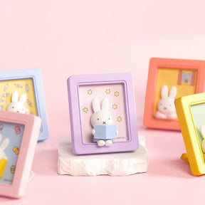 Five Miffy magnetic photo frames in pastel colors featuring small bunny figures with themed backgrounds on pink surface
