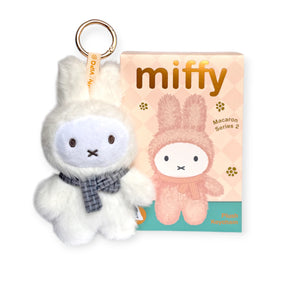 A white VIPO x Miffy Macaron 2 Plush Keychain - Blind Box by Miffy, featuring a plaid scarf, sits beside its pastel pink packaging with a cute pastel Miffy illustration.