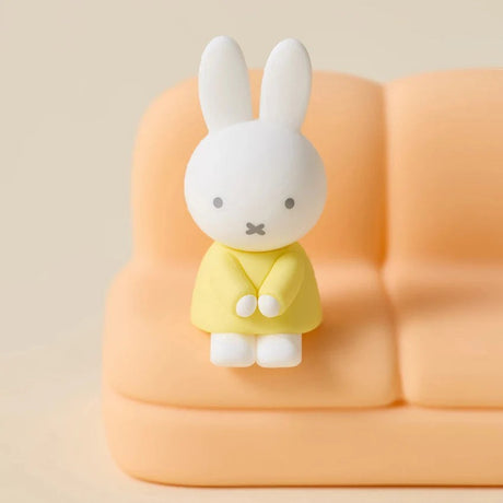 Miffy sofa phone stand with white bunny in yellow outfit on an orange seat