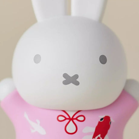 Close-up of 6cm Miffy figure wearing a pink robe with koi fish motifs on light beige background