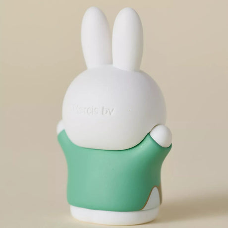 Rear view of a 6cm Miffy figure wearing a simple green ancient-inspired robe on beige background
